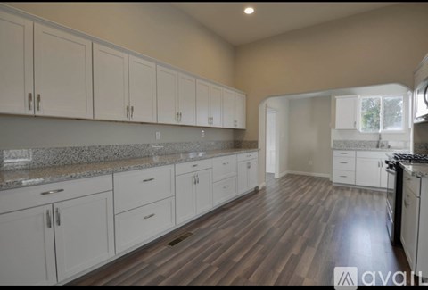 A kitchen with white cabinets and a wooden floor.