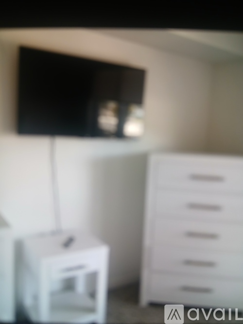A black screen is mounted on a white wall.