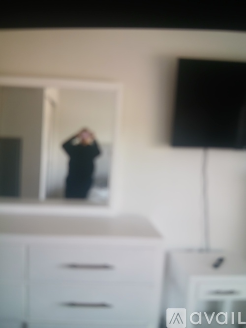 A woman in a black dress is standing in front of a mirror.