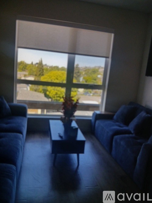 A living room with a large window and a view of a parking lot and trees.
