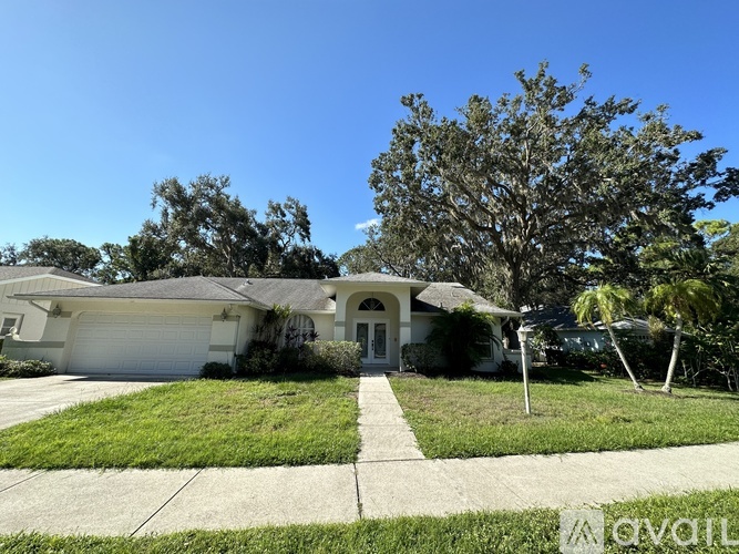 A house with a white garage door and a tree in front.
