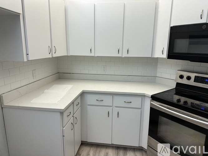 A kitchen with white cabinets and a black stove top oven.
