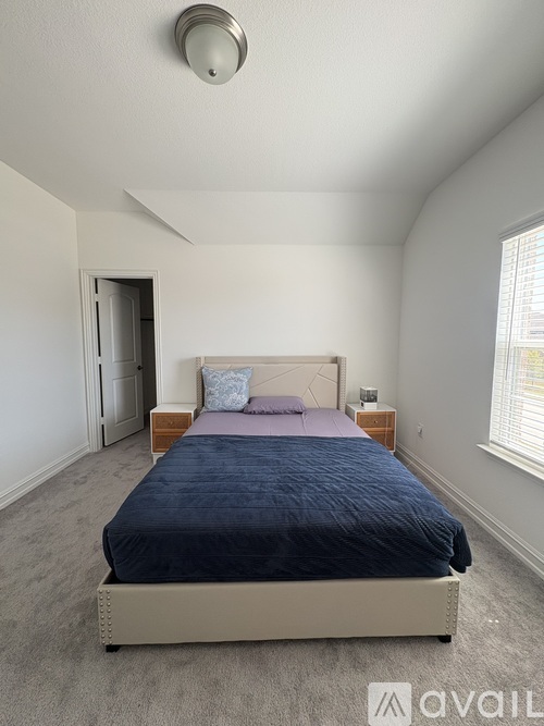 A bedroom with a bed, nightstand, and window.