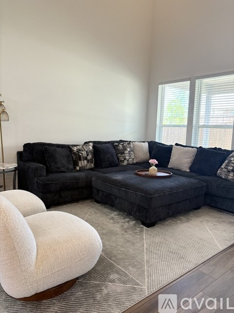 A living room with a black couch and a white chair.
