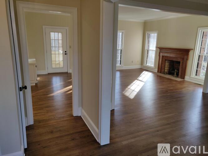 A spacious room with wooden floors and a fireplace.