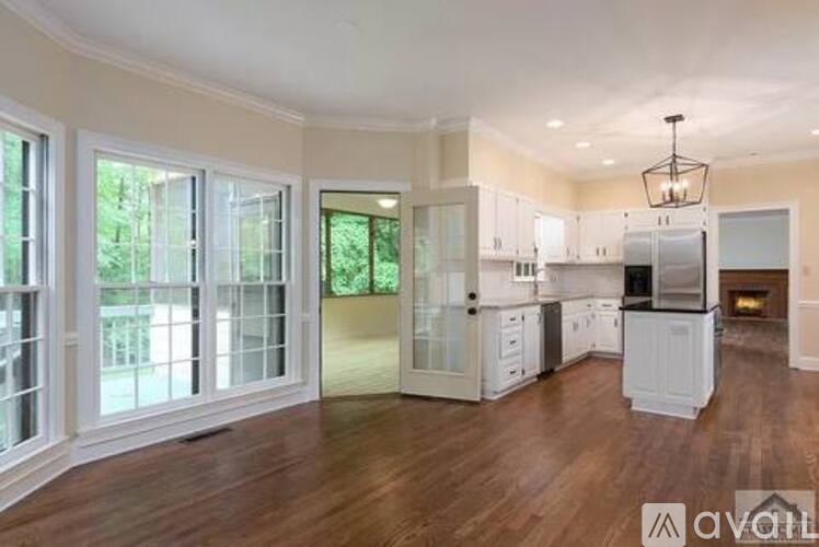 A spacious kitchen with white cabinets and a wooden floor.