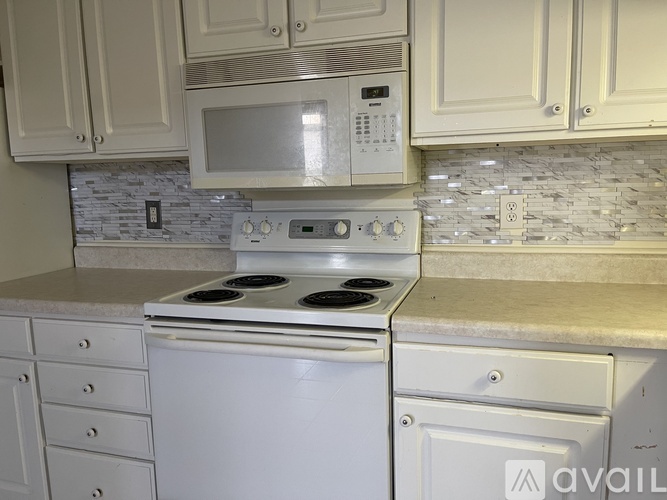 A kitchen with a white stove and microwave above it.