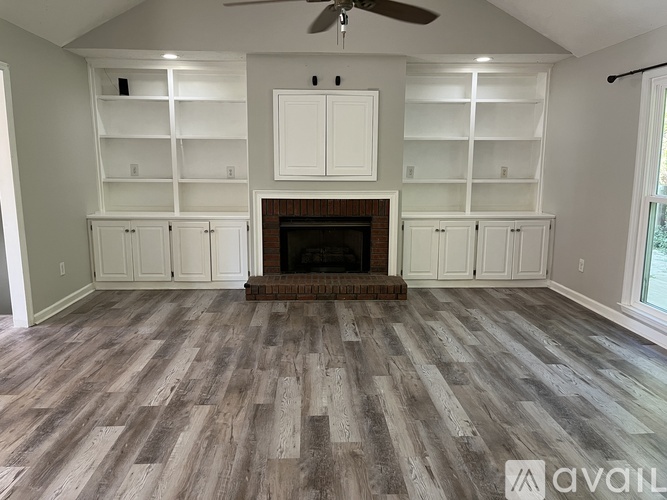 A living room with a fireplace and built-in cabinets.