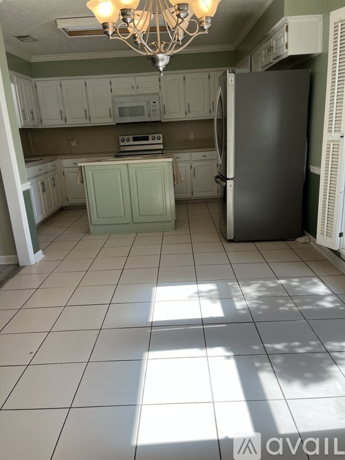 A kitchen with a black refrigerator and white cabinets.