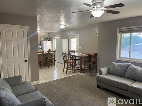 A living room with a grey couch and a dining table with chairs.