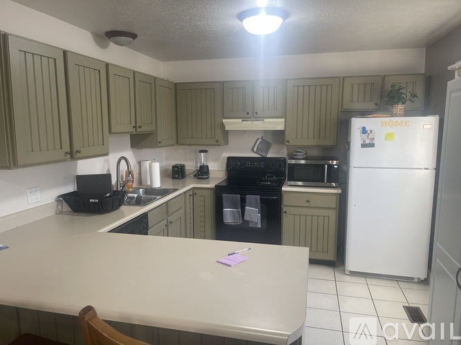 A kitchen with a white fridge and green cabinets.