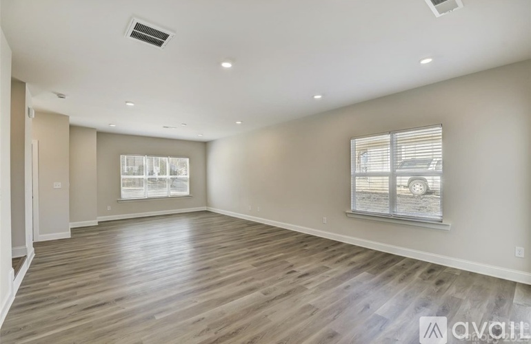 A spacious room with wooden flooring and a window with blinds.