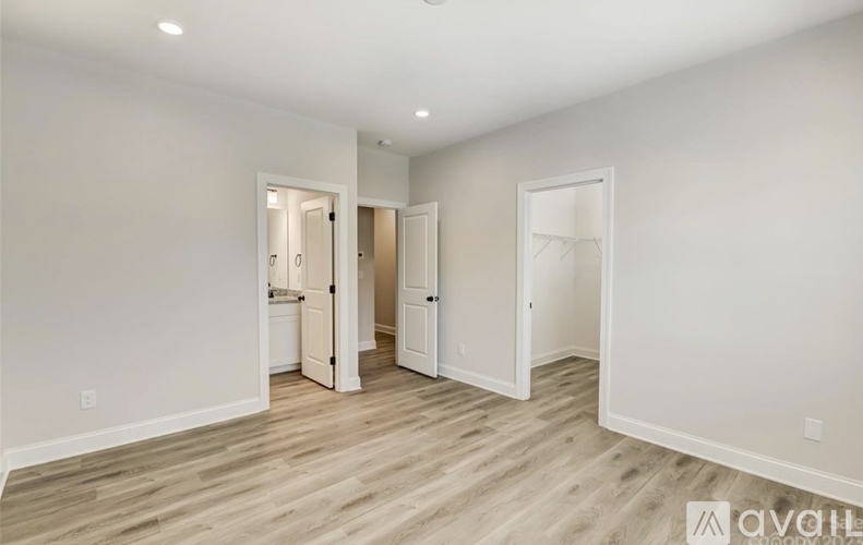 A room with white walls and wooden flooring, with two open doors leading to other rooms.