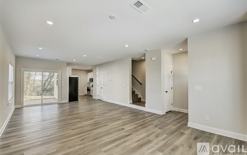 A spacious room with wooden flooring and a large window.