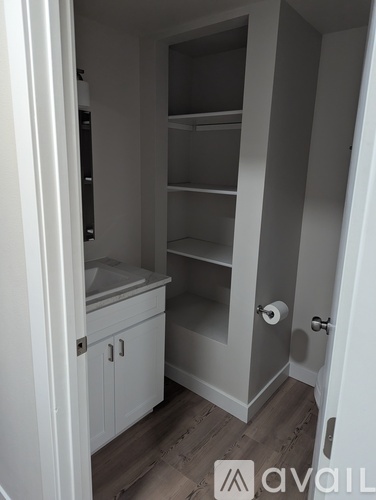 A small white kitchen pantry with a door open to a hallway.