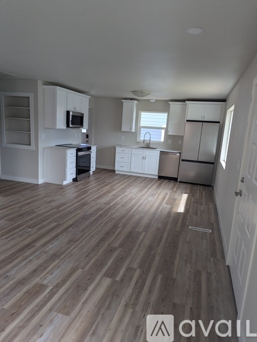 A kitchen with white cabinets and a wooden floor.