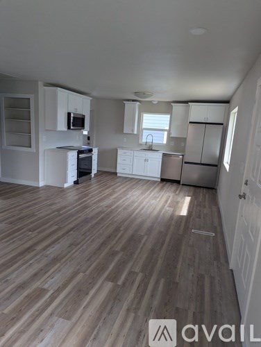 A kitchen with white cabinets and a wooden floor.