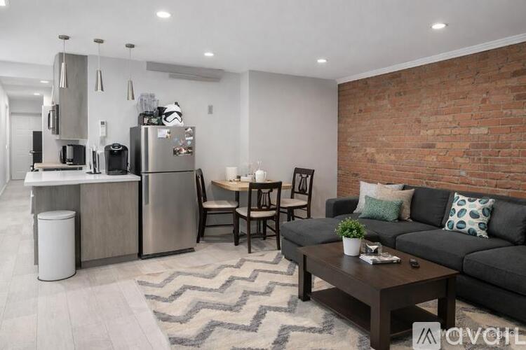 A modern kitchen with a brick wall and a black couch.