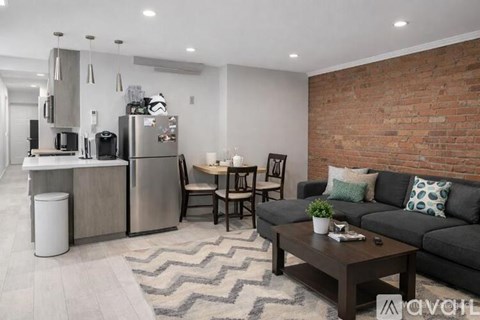 A modern kitchen with a brick wall and a black couch.