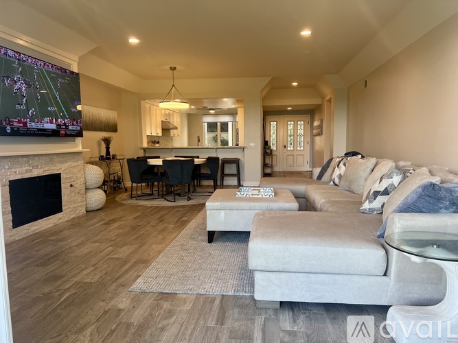 A modern living room with a fireplace and a television displaying a football game.