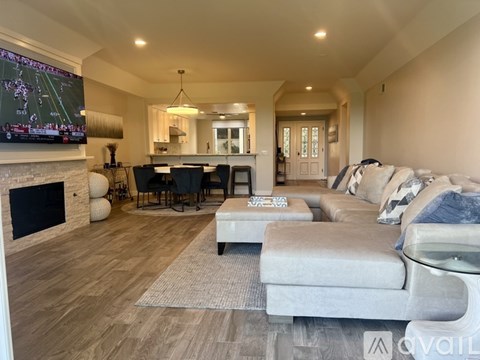 A modern living room with a fireplace and a television displaying a football game.