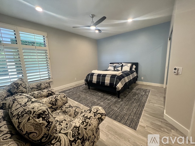 A bedroom with a patterned bedspread and a black and white checkered ottoman.