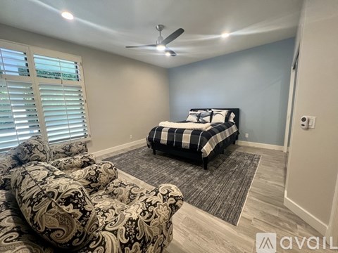 A bedroom with a patterned bedspread and a black and white checkered ottoman.