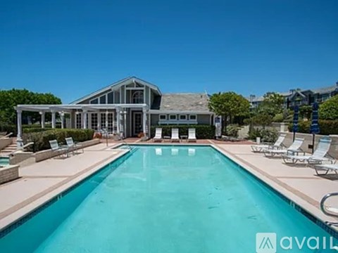 A large swimming pool in front of a house with a sign that says "available".