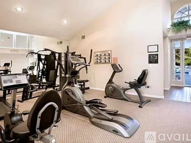 A gym with a variety of exercise equipment including treadmills, stationary bikes, and weight machines.