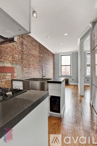 A kitchen with a brick wall and wooden floors.