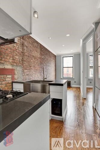 A kitchen with a brick wall and wooden floors.