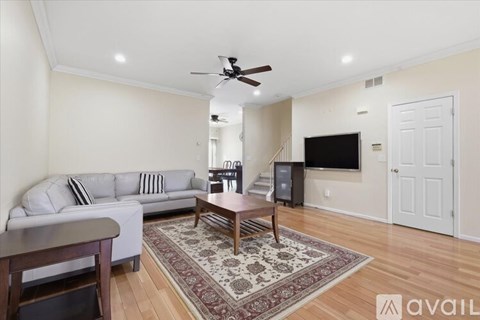 A living room with a white couch and a rug on the floor.