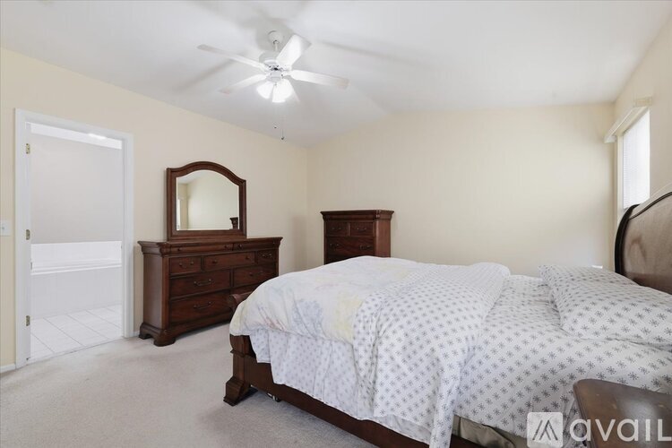 A bedroom with a bed, dresser, mirror, and a ceiling fan.