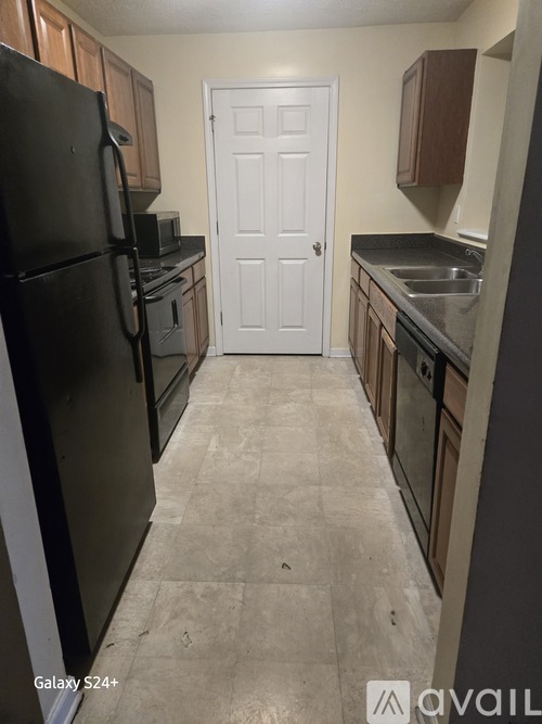 A kitchen with a black fridge and a white door.