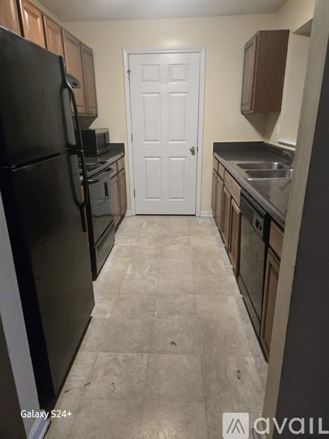 A kitchen with a black fridge and a white door.