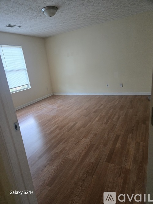 A room with wooden flooring and a window.
