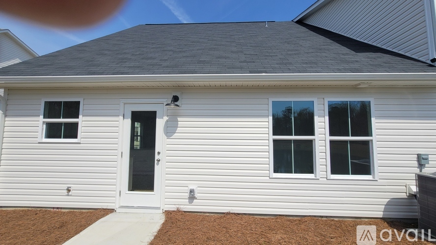 A white house with a black roof and a grey garage door.