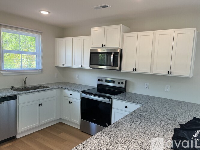 A kitchen with white cabinets and granite countertops.
