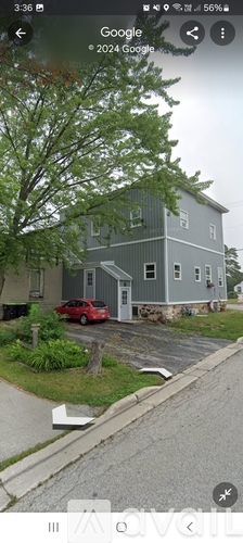 A grey house with a red car parked in front.
