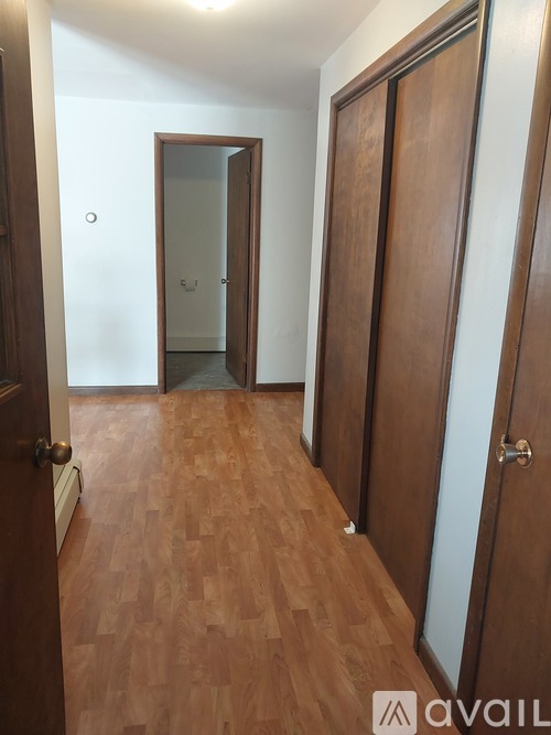 A hallway with a wooden floor and a white door.