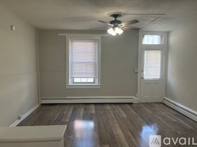 A room with a ceiling fan and wooden flooring.