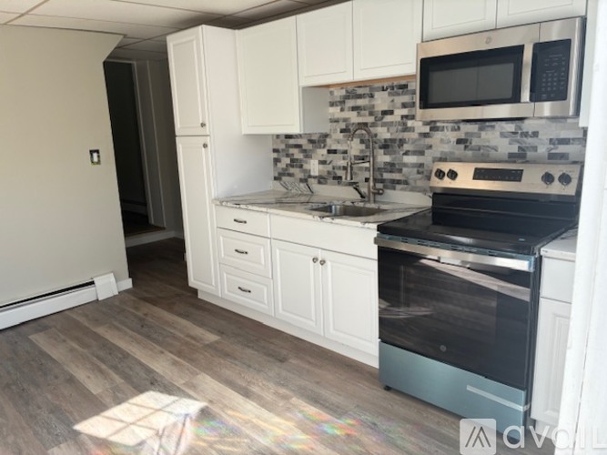 A kitchen with a black stove top oven and white cabinets.