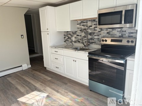 A kitchen with a black stove top oven and white cabinets.