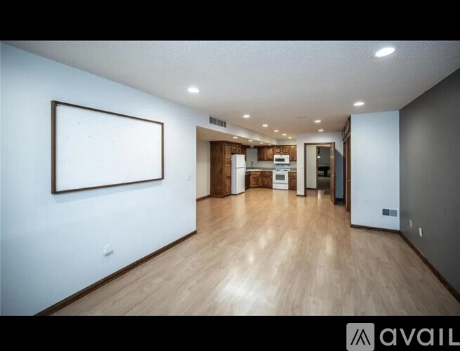 A spacious room with wooden floors and a framed picture on the wall.