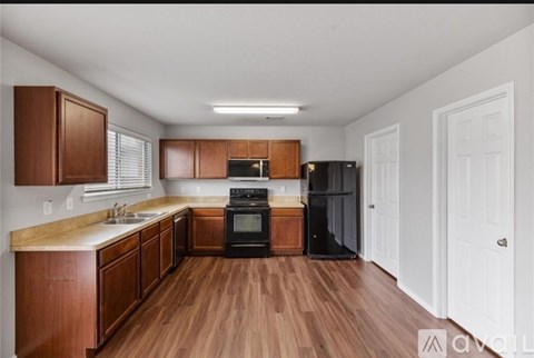 A kitchen with wooden cabinets and a black refrigerator.