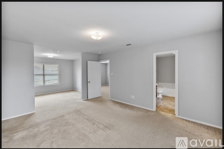 A spacious, empty room with a carpeted floor and white walls.