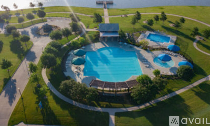 An aerial view of a swimming pool surrounded by a grassy area and trees.
