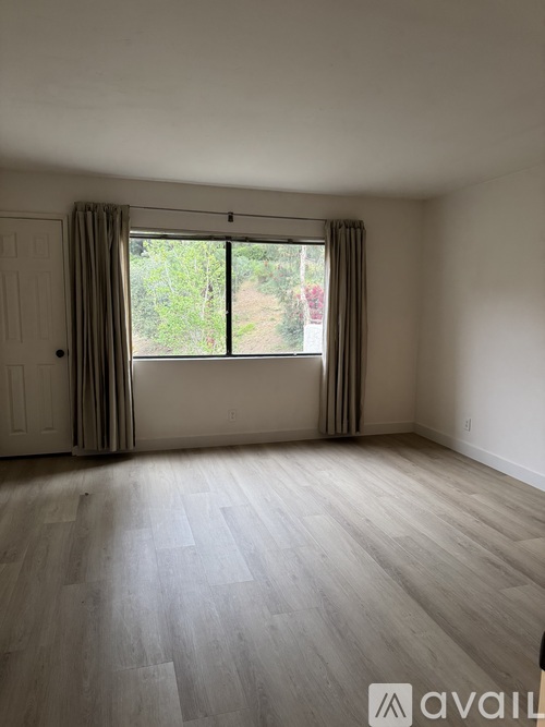 A room with a large window and a wooden floor.