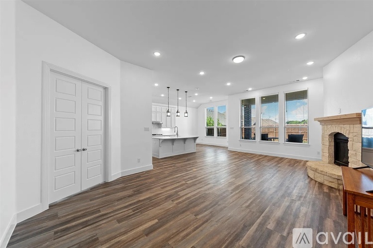 A spacious room with wooden floors and a fireplace.