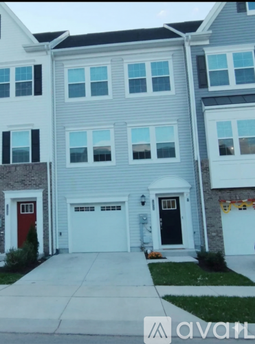 A grey and white two story house with a red door.